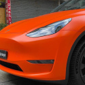 Zbliżenie na przód tesli y. Samochód pokryty folią chroma guard w kolorze pomarańczowym z wykończeniem satnynowym.